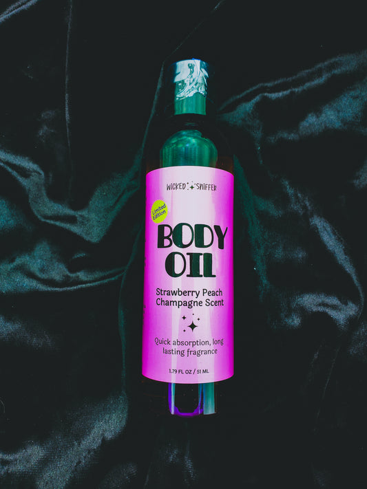 Bottle of body oil with a pink label on a dark fabric background
