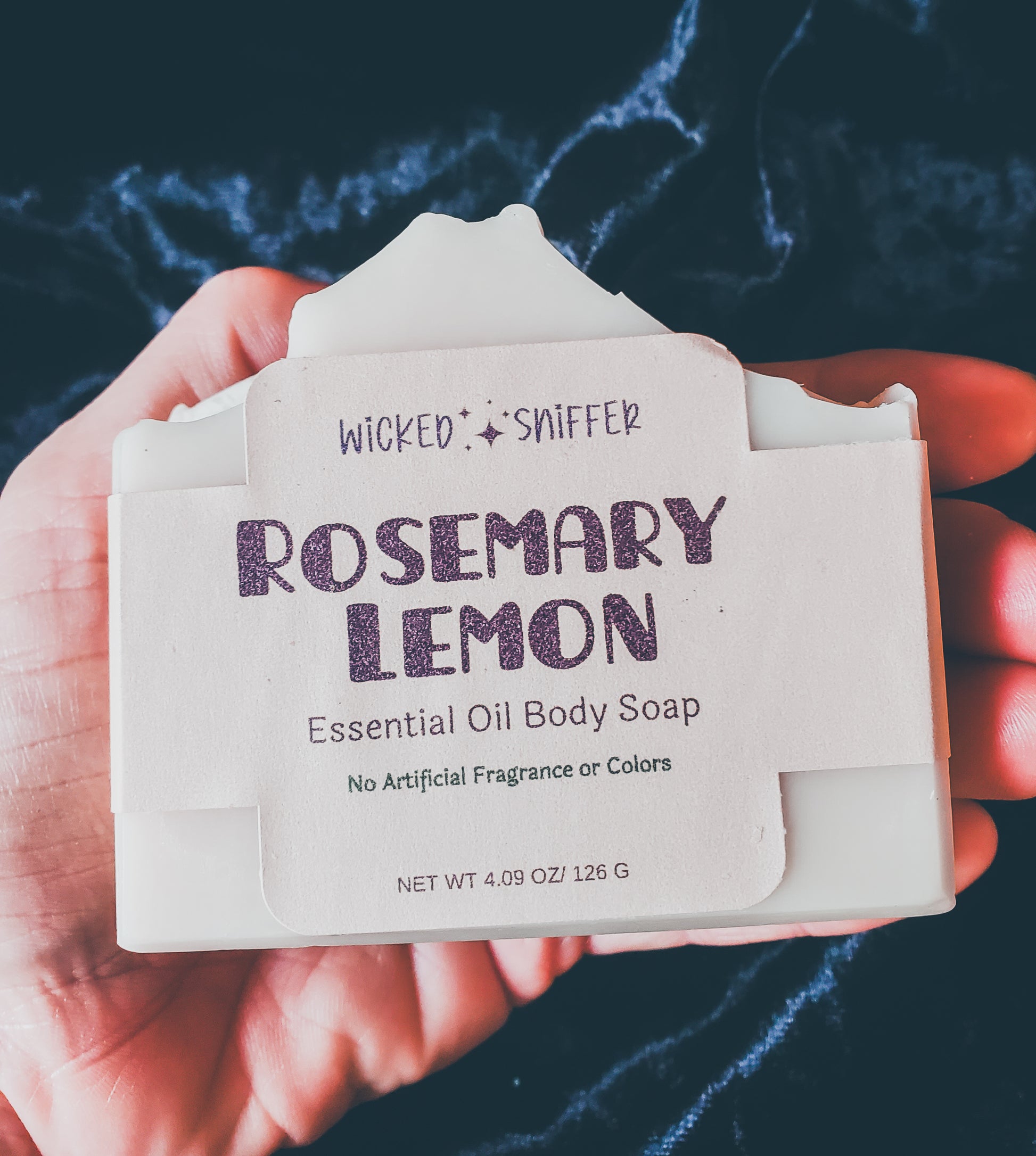 Hand holding tan soap on a black background