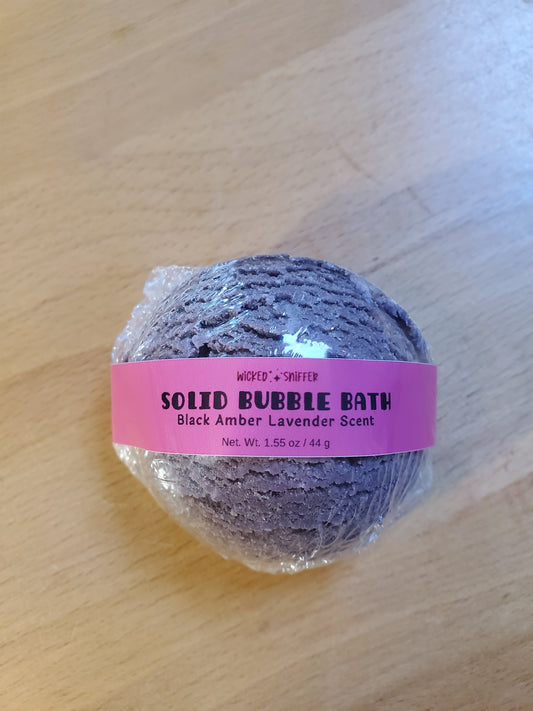 Solid bubble bath ball with a pink label on a wooden surface