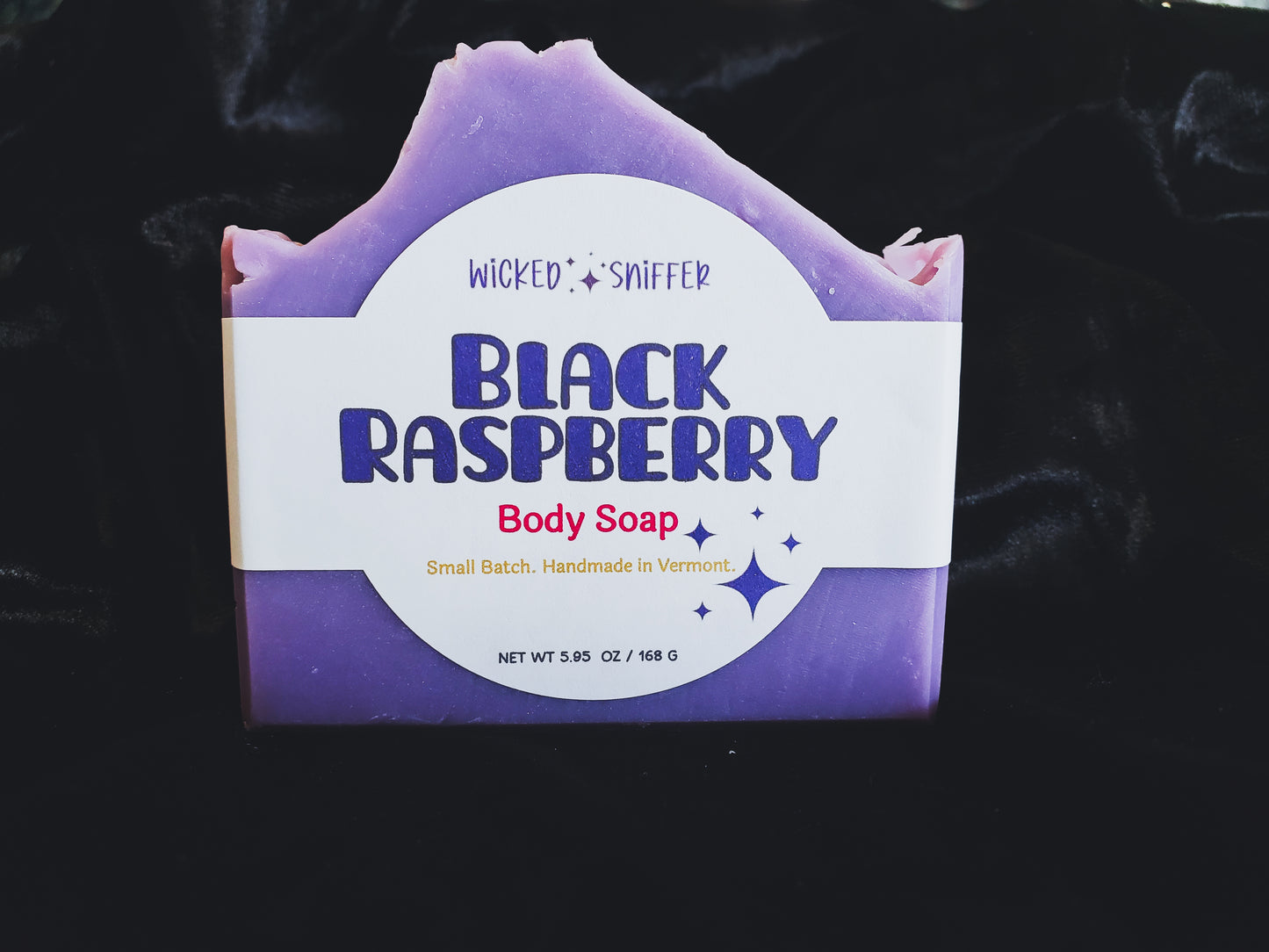 Purple bar of soap with 'Black Raspberry' and 'Wicked & Sniffer' branding on a black background