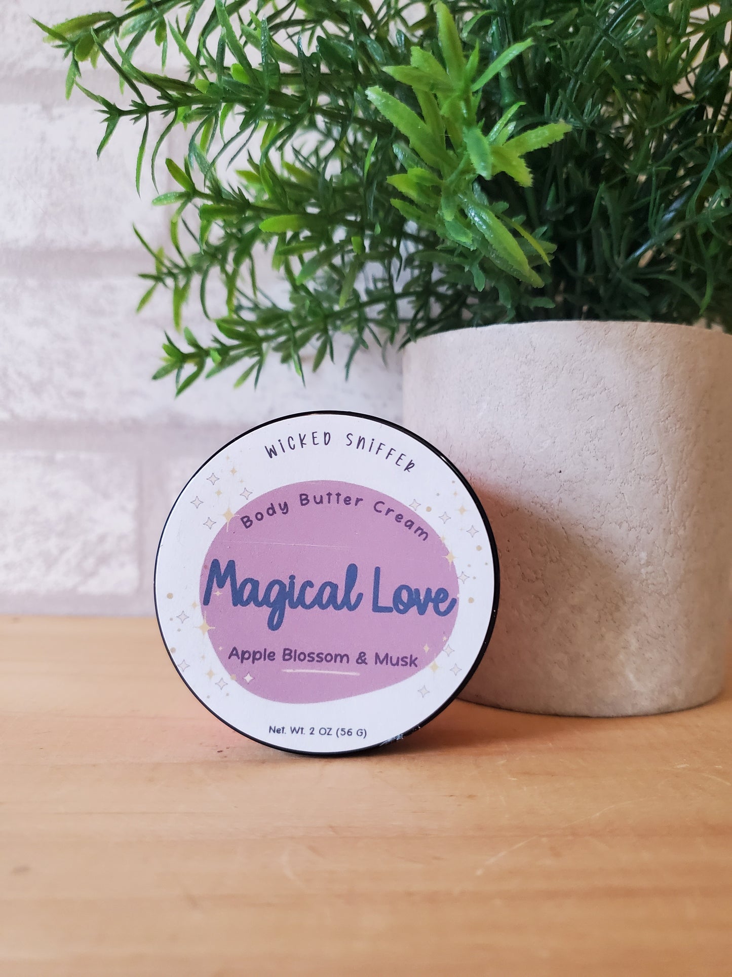 Jar of 'Magical Love' body butter cream with a plant on a wooden surface