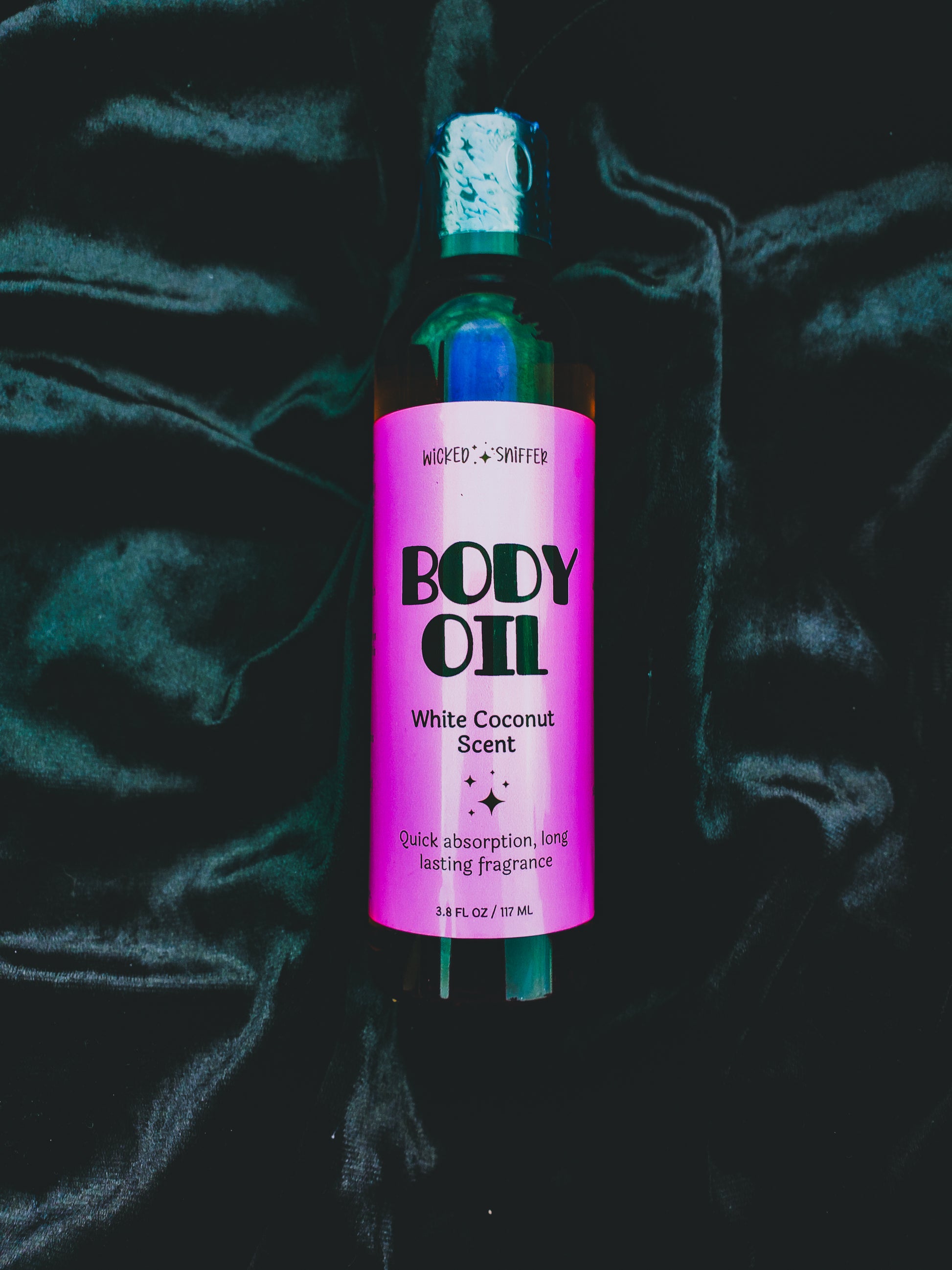 Bottle of body oil with a pink label on a dark textured background