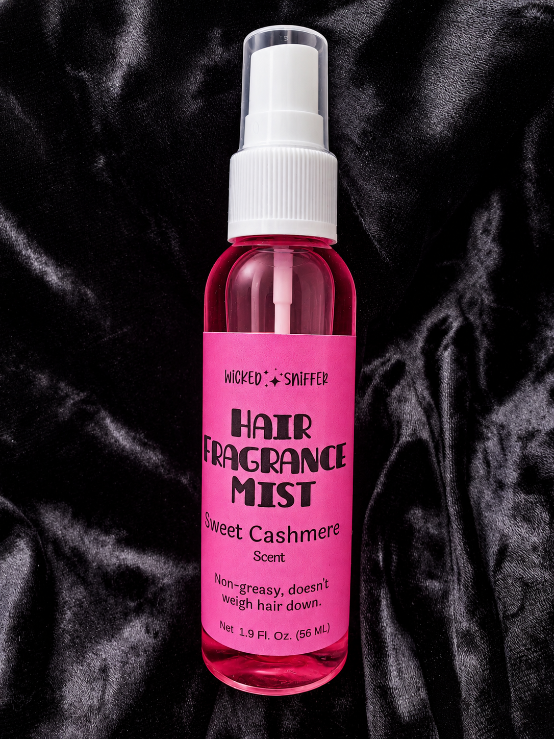 Hair fragrance mist bottle with pink label on a black textured background